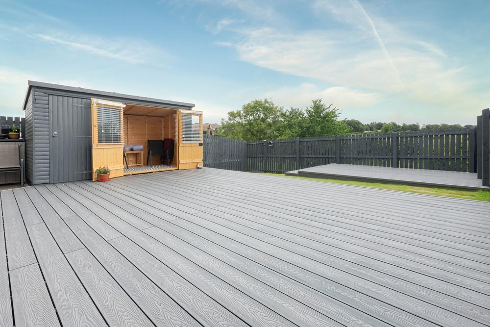 new grey outdoor deck in backyard next to a shed