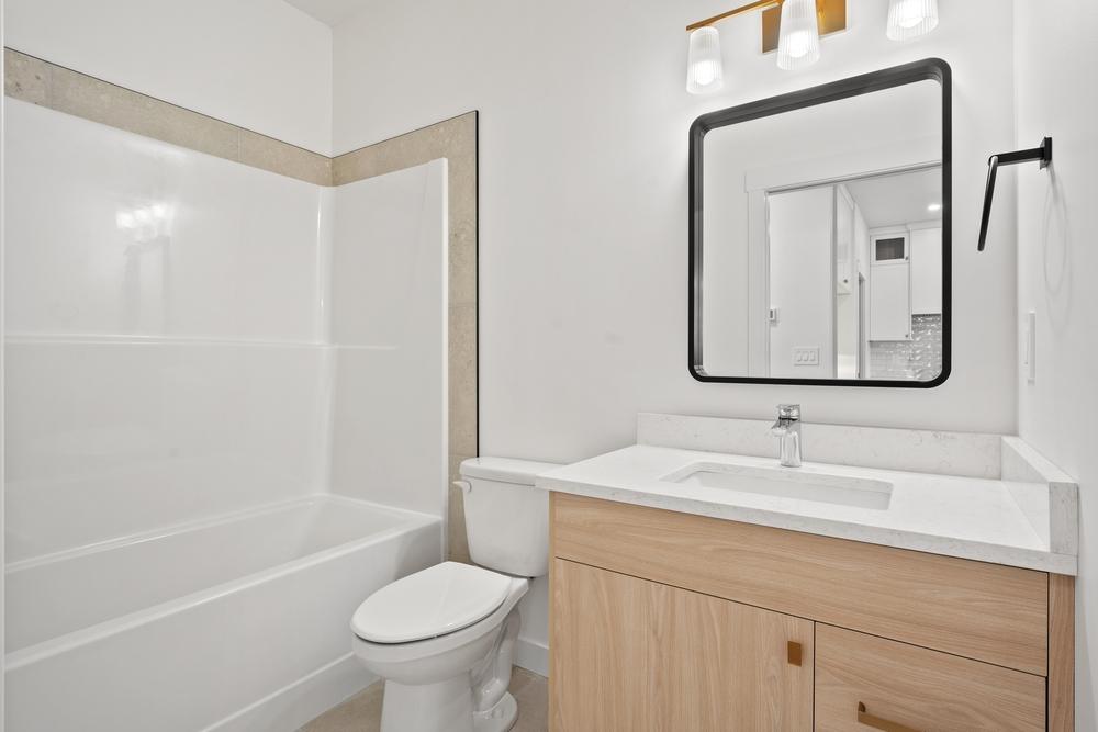 white bathroom freshly renovated with wood cabinets