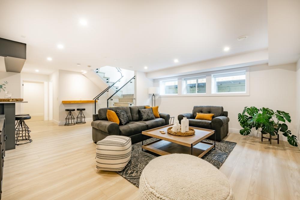 brand new basement with black leather couches, and hardwood flooring