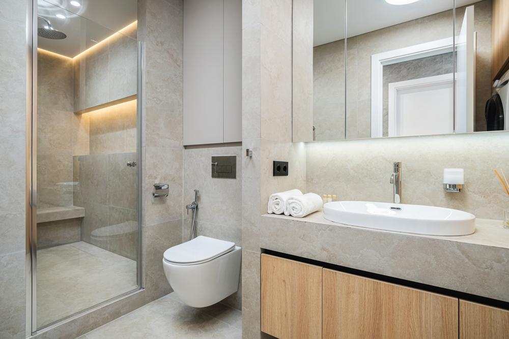 Renovated bathroom showcases a minimalist design with large tiles, a glass-enclosed shower, floating vanity, and natural light