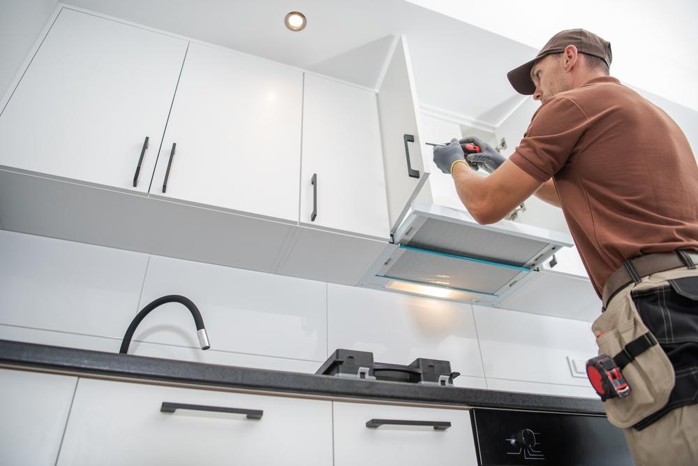 Contractor wearing brown, installing white cabinets in new kitchen